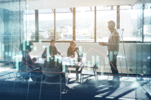 Digitally enhanced shot of a group of businesspeople meeting in the boardroom superimposed over a graph showing the ups and downs of the stock market